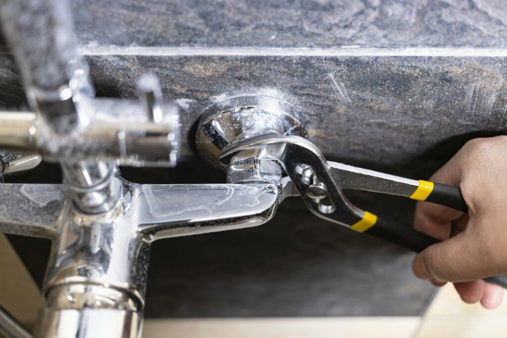 plumber unscrews nut of shower faucet close up